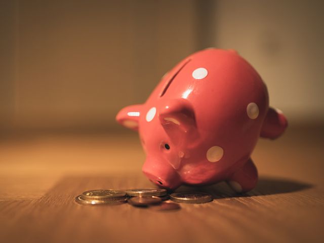 tipped piggy bank with coins on the table