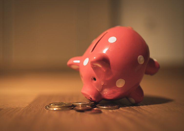 tipped piggy bank with coins on the table